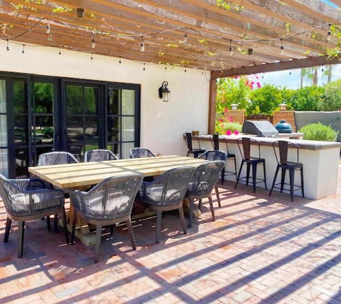 Brick patio under a pergola with a long teak dining table and rope chairs, Scottsdale