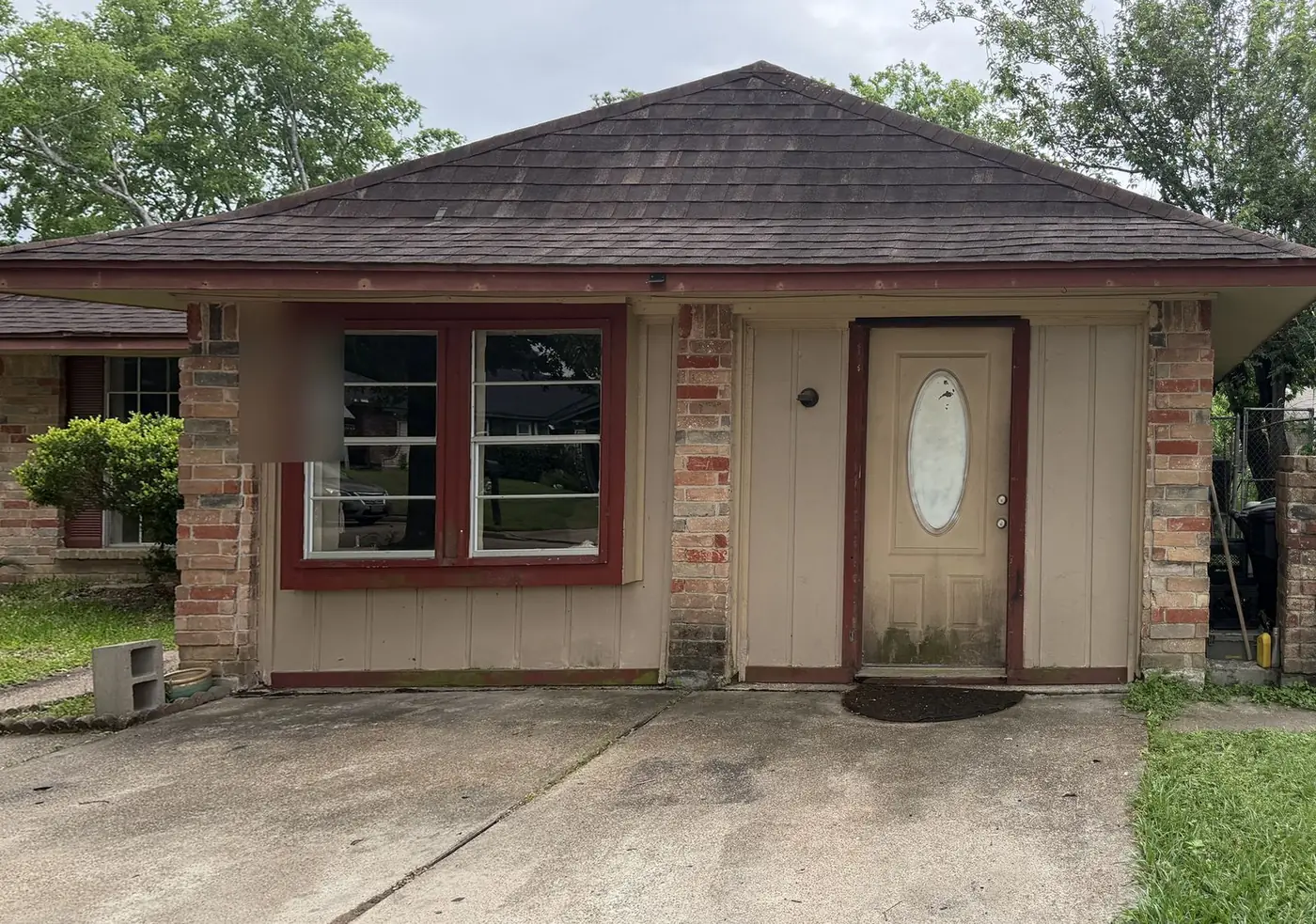 Real as-is house before renovation, with weathered brick porch, timber siding and original front door