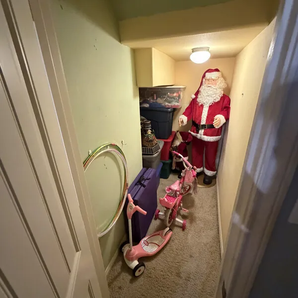 Before purchase: a hallway closet still full of a family's belongings, including a Santa figure and a child's bike